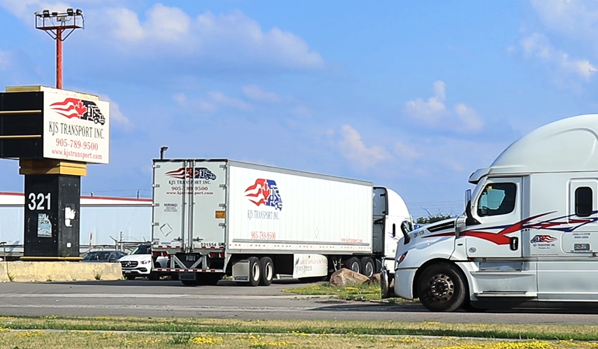 The KJS Transport Inc. sign at 321 Orenda Road, Brampton, with company tractors and trailers parked in the yard behind it