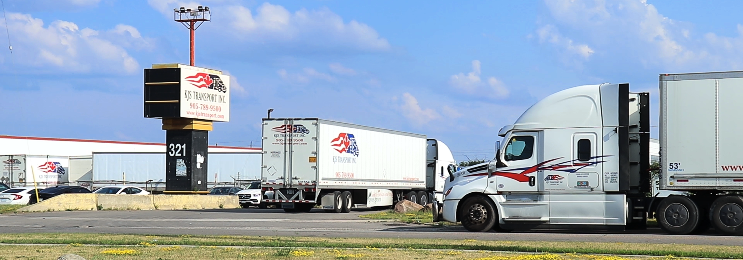 The KJS Transport Inc. sign at 321 Orenda Road, Brampton, with company tractors and trailers parked in the yard behind it