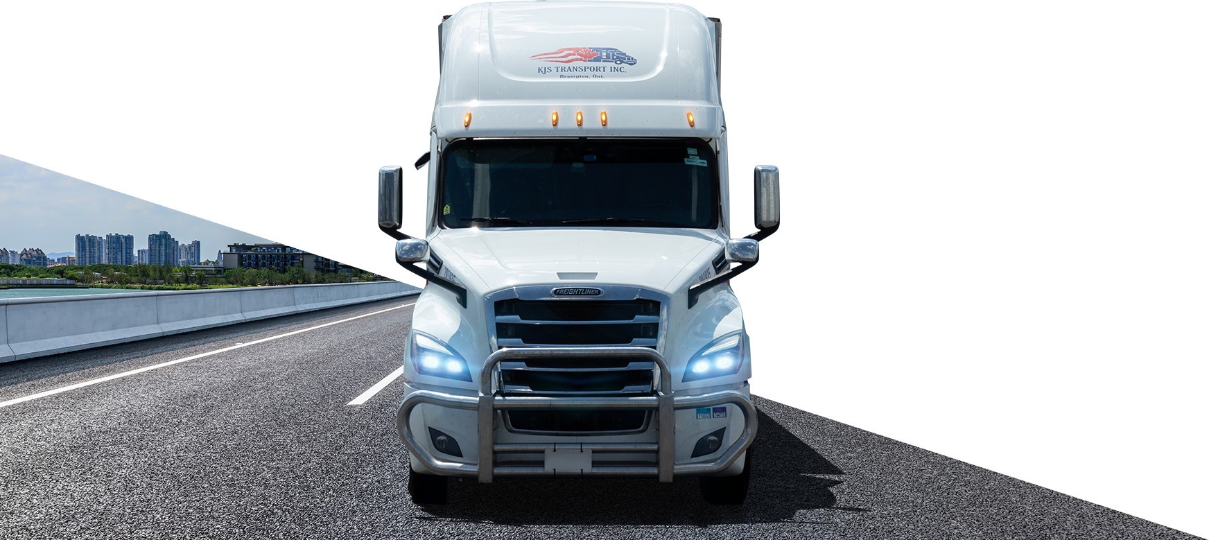 A white KJS Transport Freightliner truck on a bridge highway